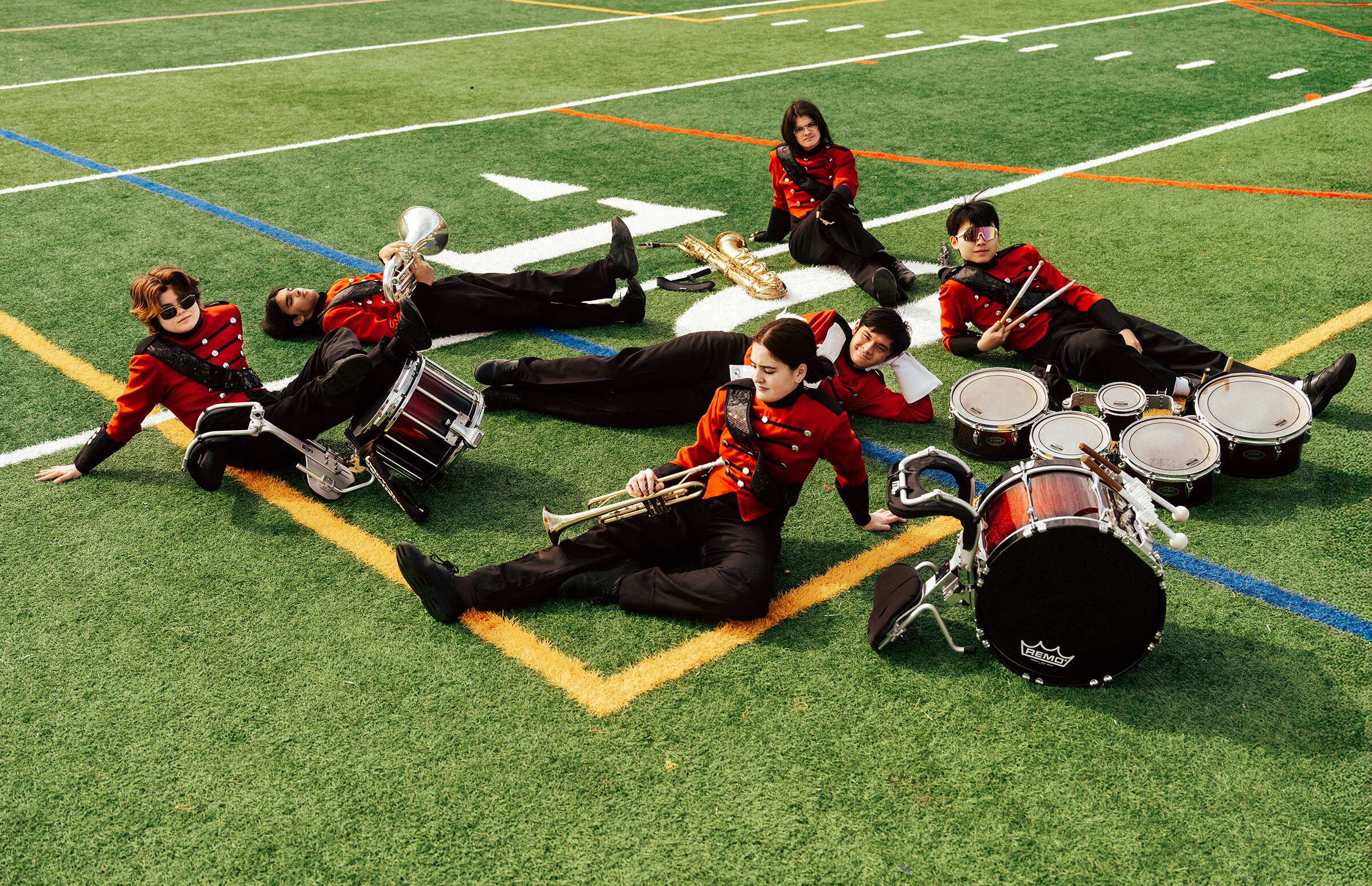 Marching band seniors lounging on the football field with their instruments, aerial view